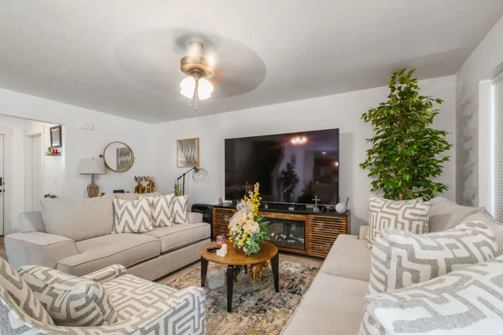 Open concept living space featuring a ceiling fan with integrated lighting, wood-finish flooring, and white painted walls