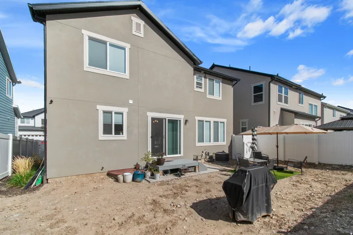 Rear exterior featuring a stucco finish, white-framed windows, and a black shingle roof