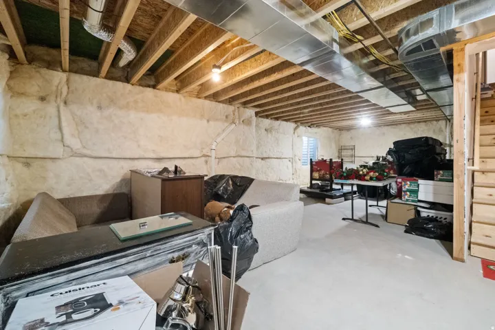 Unfinished basement featuring exposed wood joists, ductwork, and insulation-lined walls