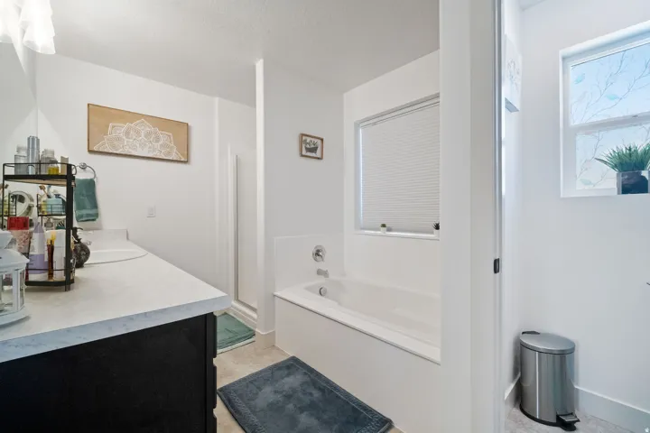 Bathroom featuring a white built-in bathtub, a separate shower enclosure, and a vanity with a light-colored countertop