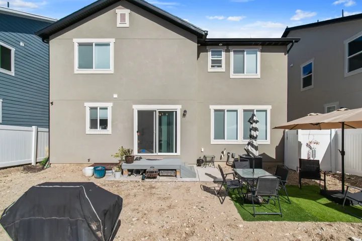Rear exterior featuring a sliding glass door, multiple windows with white trim, and a patio area