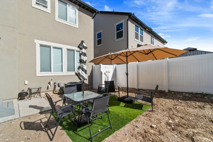 Patio area featuring a concrete pad, a white vinyl fence, and a portion of the building's exterior