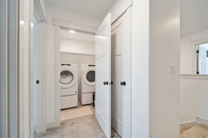 Dedicated laundry area featuring white appliances, a light-colored rug, and built-in shelving