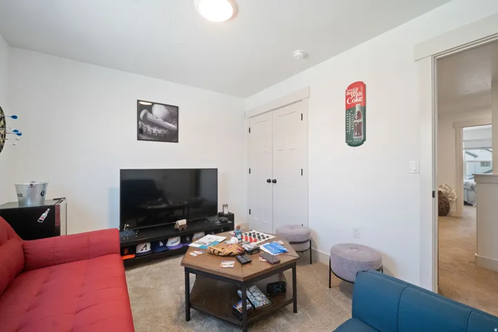 Carpeted room featuring white walls, a built-in television console, and white double doors with black hardware