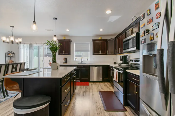 Modern kitchen featuring dark wood cabinetry, light countertops, and stainless steel appliances