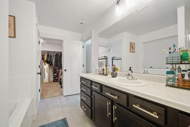 Bathroom featuring a single basin vanity with dark wood cabinetry and gold-tone hardware