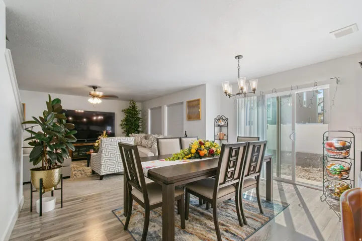 Open-concept living and dining area featuring wood-finish flooring, a contemporary chandelier, and sliding glass doors providing access to the outdoor space