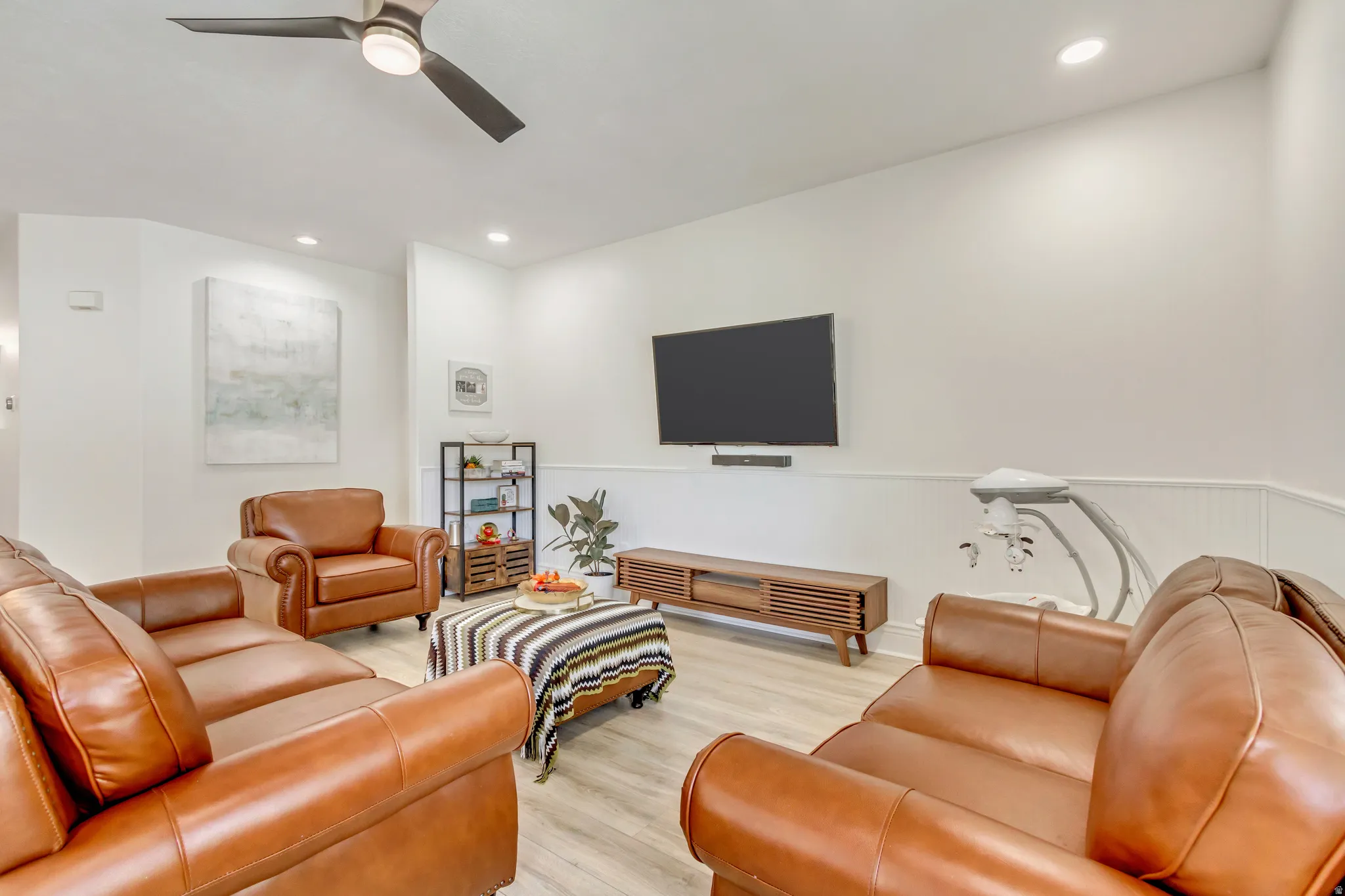 Spacious living area featuring light wood-finish flooring, recessed lighting, and a ceiling fan