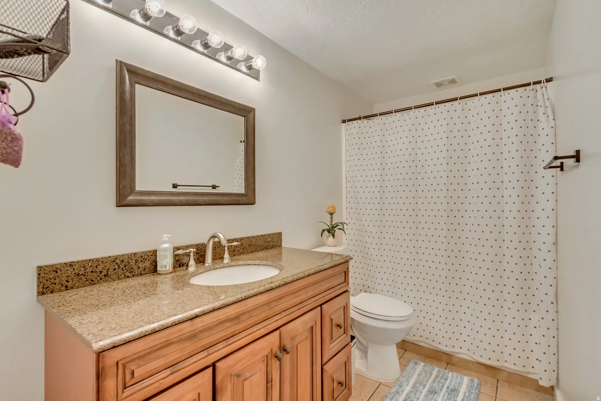 Bathroom vanity featuring a stone-finish countertop, undermount sink, and wood-finish cabinetry