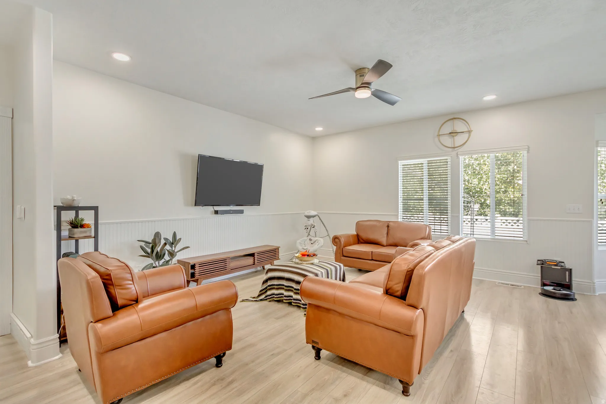 Spacious living area featuring light wood-finish flooring, recessed lighting, and a ceiling fan