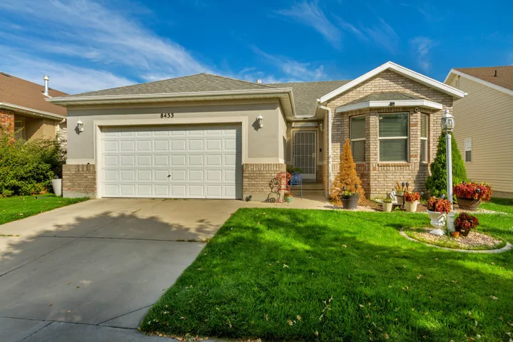 Exterior showcasing a two-car garage, partial brick facade, bay window, and a concrete driveway