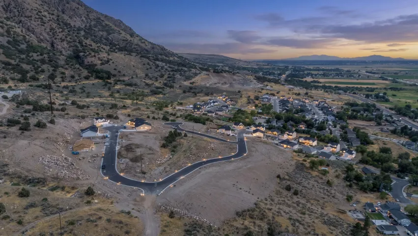 New construction homes situated on a winding paved road, with mountainous terrain as a backdrop
