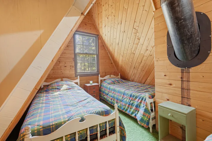 Wood-paneled room featuring a window with exterior tree views, sloped ceilings, and wood-finish flooring
