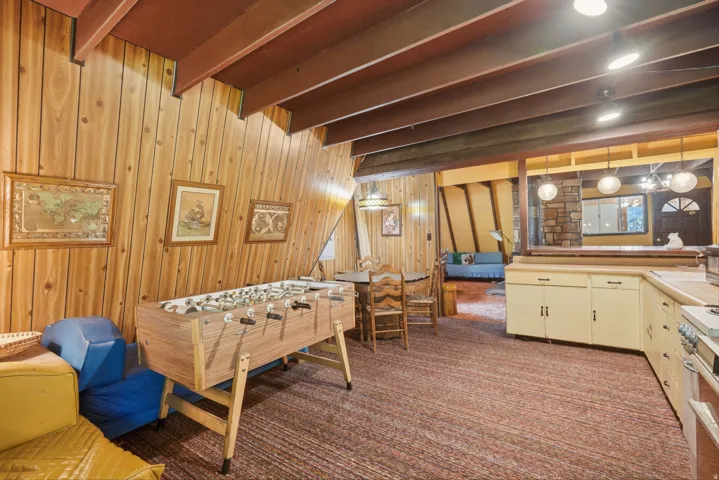 Sloped wood panel walls with exposed ceiling beams and recessed lighting