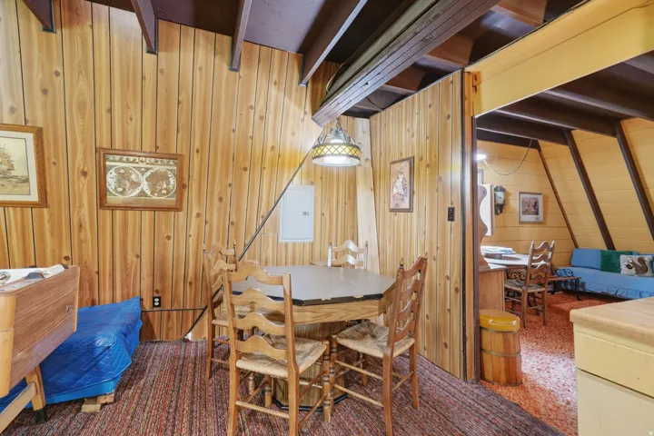 Wood-paneled interior featuring exposed ceiling beams and a hanging light fixture