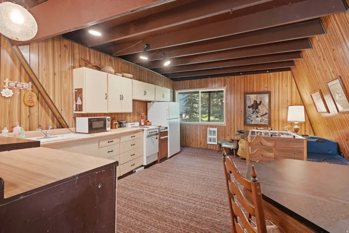 Open-concept living area featuring a full kitchen with light-toned cabinetry and white appliances