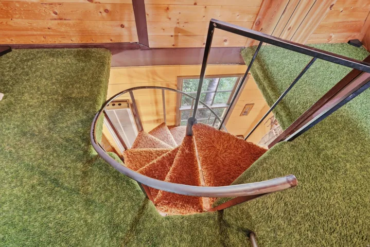 Spiral staircase with orange shag carpeted treads, framed by a metal railing