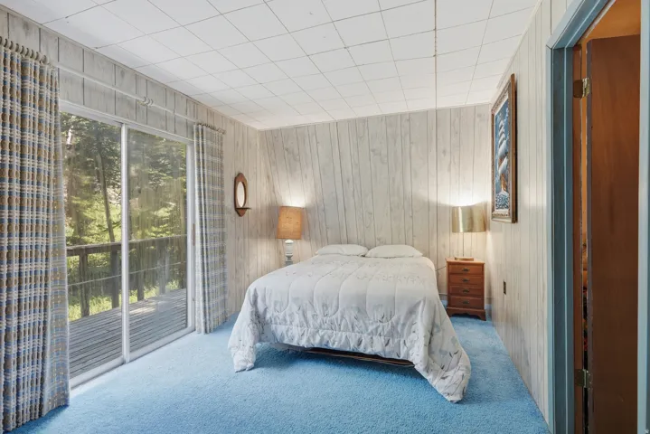 Room featuring wood-paneled walls, blue carpeting, and a white grid ceiling