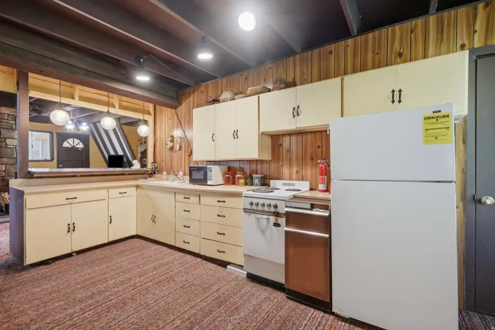Kitchen area featuring wood paneling, light-toned cabinetry, and a U-shaped countertop