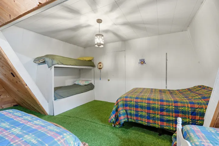 Room featuring a built-in bunk bed, white paneled walls, a sloped wood-paneled ceiling, and a green carpeted floor