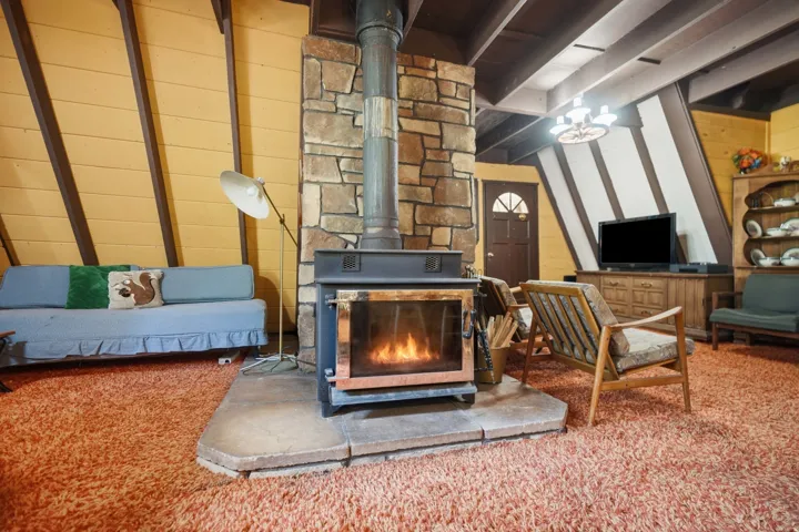 Central stone-clad fireplace with a wood-burning stove and stone hearth