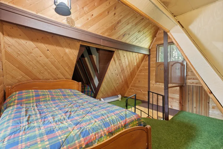 Wood-paneled room featuring sloped walls, green carpeted flooring, and a metal railing