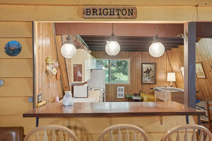 Wood-finish breakfast bar with integrated seating, illuminated by three hanging globe pendant lights