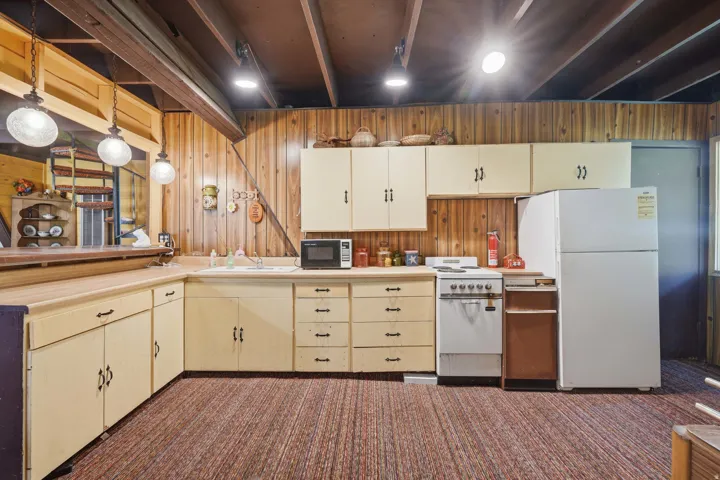 Kitchen area featuring wood-paneled walls and exposed ceiling beams