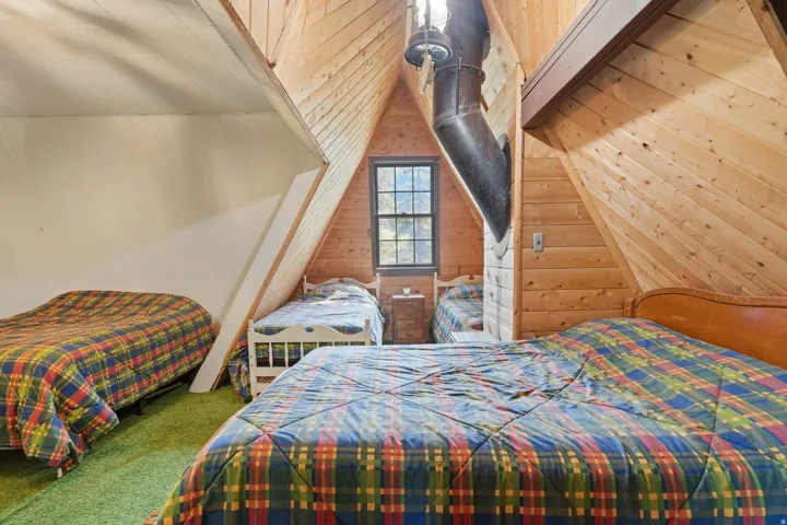 Attic room featuring natural wood-paneled walls and sloped ceilings