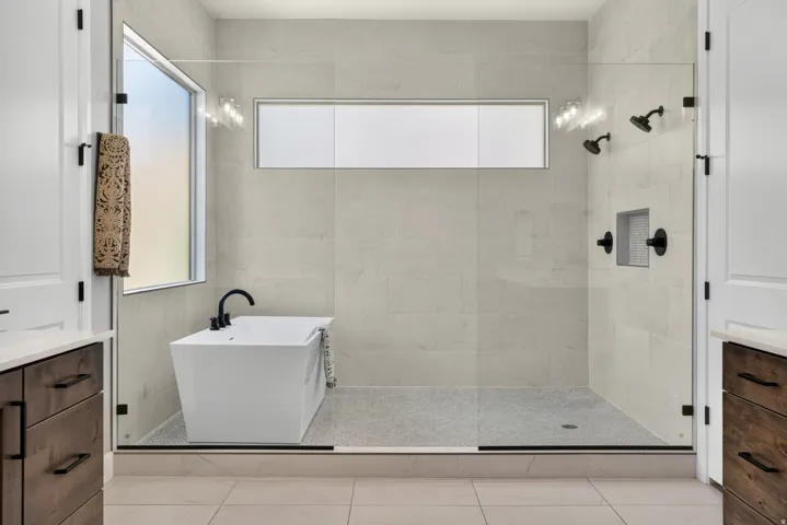 Spacious walk-in shower with a freestanding soaking tub, dual shower heads, and built-in shelving