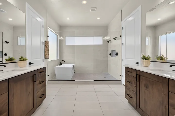 Contemporary bathroom featuring dual wood-finish vanities with quartz countertops and undermount sinks, a freestanding soaking tub, a spacious glass-enclosed shower with multiple showerheads, and recessed lighting