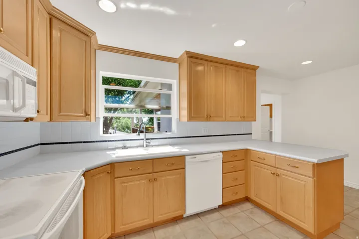 Kitchen featuring light wood cabinetry, white countertops, tile backsplash, and recessed lighting