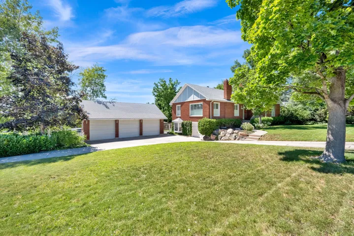 Brick residence featuring a white gable accent, a prominent chimney, and a stone-lined garden bed