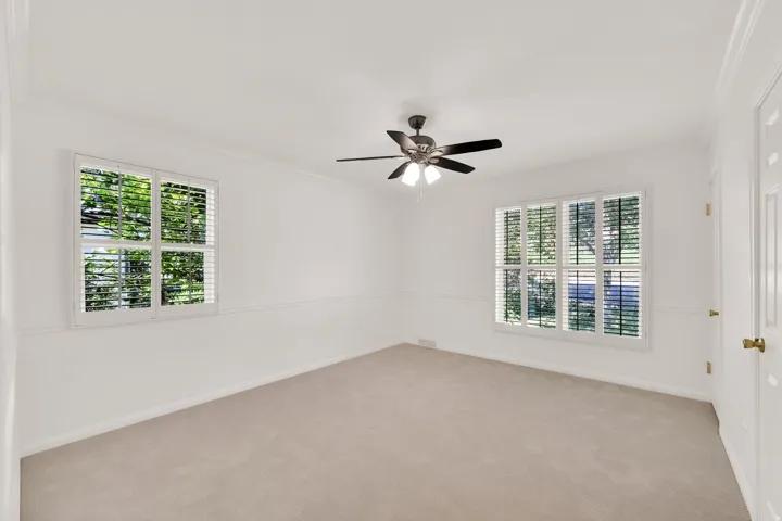 Spacious room featuring neutral carpeting, white walls, and crown molding