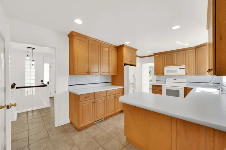 Kitchen featuring wood-finish cabinetry, white countertops, subway tile backsplash, and recessed lighting
