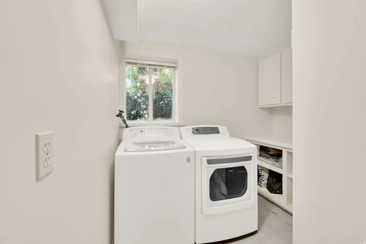 Laundry area featuring built-in cabinetry, open shelving, and a window