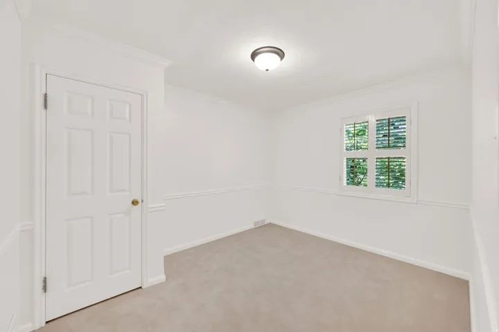 Room featuring neutral-toned carpet, white painted walls with chair rail molding, and a window with white louvered blinds