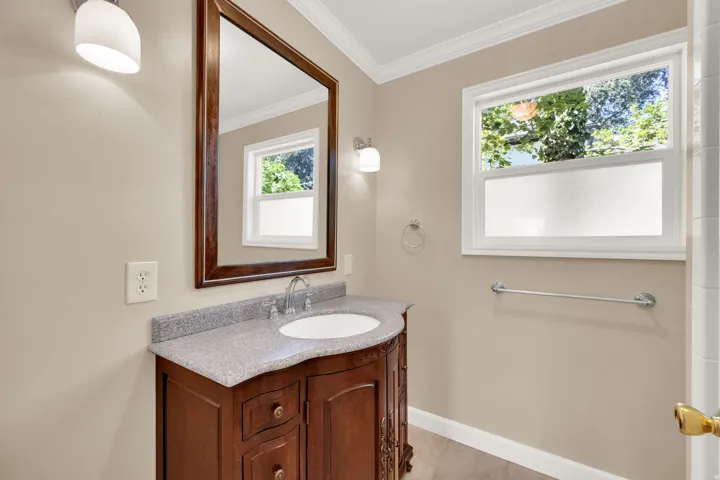 Bathroom vanity featuring a curved wood-finish base, integrated basin, and speckled countertop