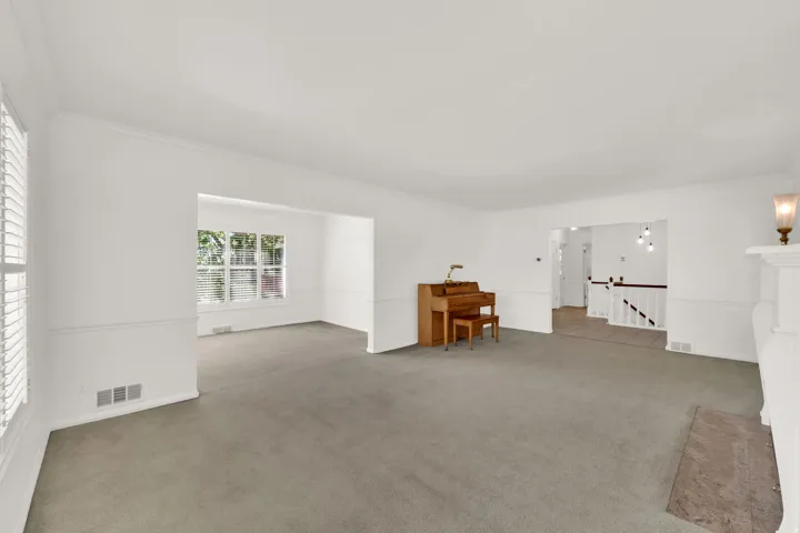 Spacious interior featuring neutral carpeting, white wall paint, and a white crown molding trim