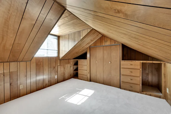 Attic space featuring wood-paneled walls and ceiling