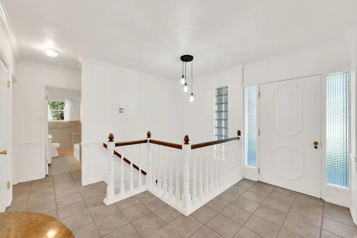 Entry foyer featuring a white paneled door with sidelights, staircase with white balusters and wood handrail, and pendant light fixture