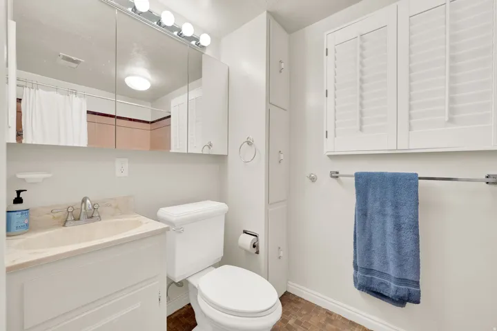 Full bathroom featuring a single vanity with a solid surface countertop, white cabinetry, a built-in medicine cabinet, and a toilet