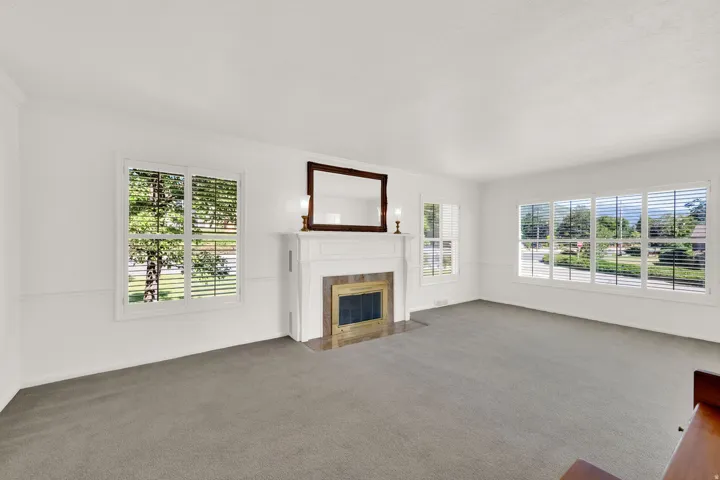 Living area featuring a white mantel fireplace with a tiled surround, crown molding, chair rail molding, and multiple windows with white blinds