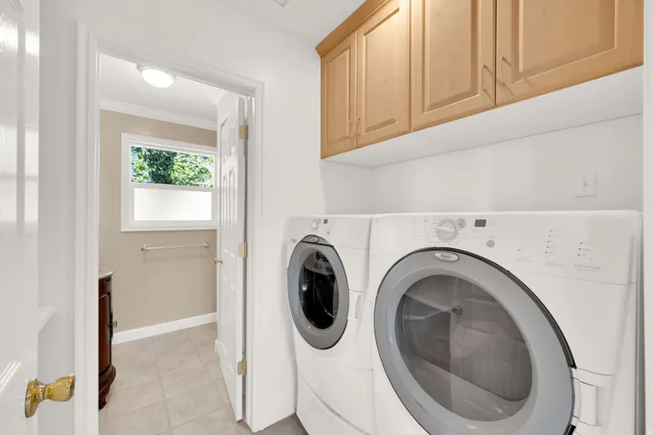 Dedicated laundry area featuring stacked appliances and light wood cabinetry