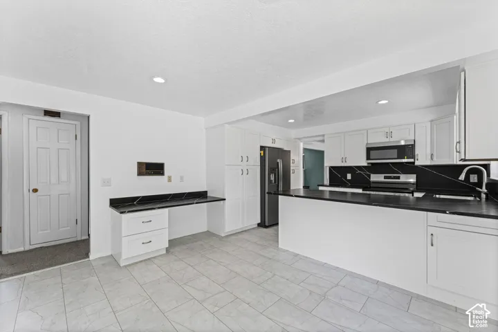 Bright kitchen with white cabinetry and black countertops