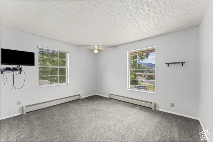 Carpeted interior space featuring light-colored walls and a textured ceiling