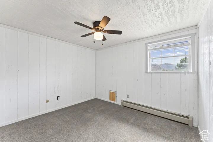 Room featuring white vertical paneling, light gray carpeting, and a window with blinds