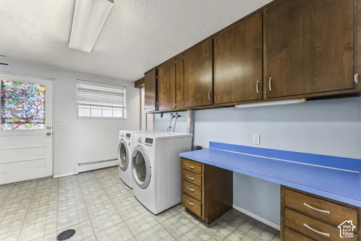 Dedicated laundry area featuring a front-load washer and dryer, ample upper cabinetry, a built-in countertop with integrated drawers, and patterned floor tiling
