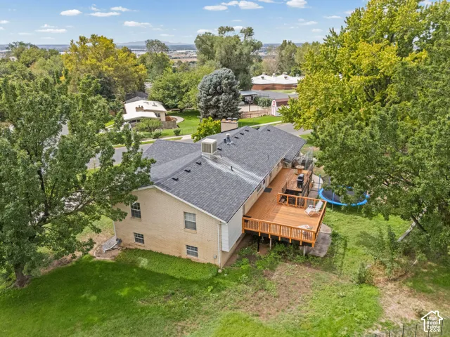 Expansive rear deck, mature trees, and a shingled roof