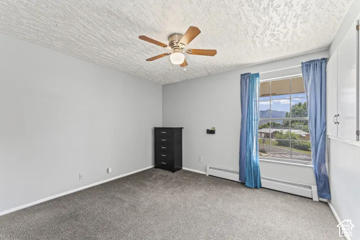 Carpeted room featuring a ceiling fan with light fixture, a large window, and built-in white cabinetry